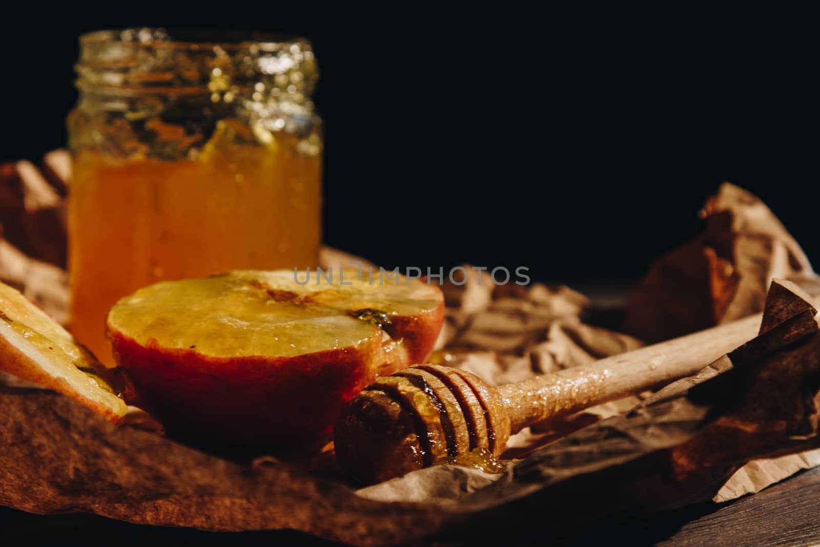 Honey with wooden honey dipper paper napkin and fruits on wooden table close up by yulaphotographer