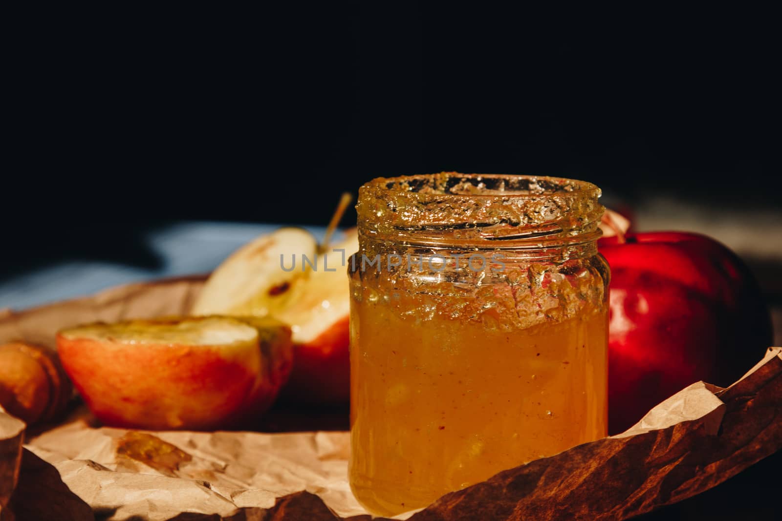 Honey with wooden honey dipper and fruits on wooden table close up