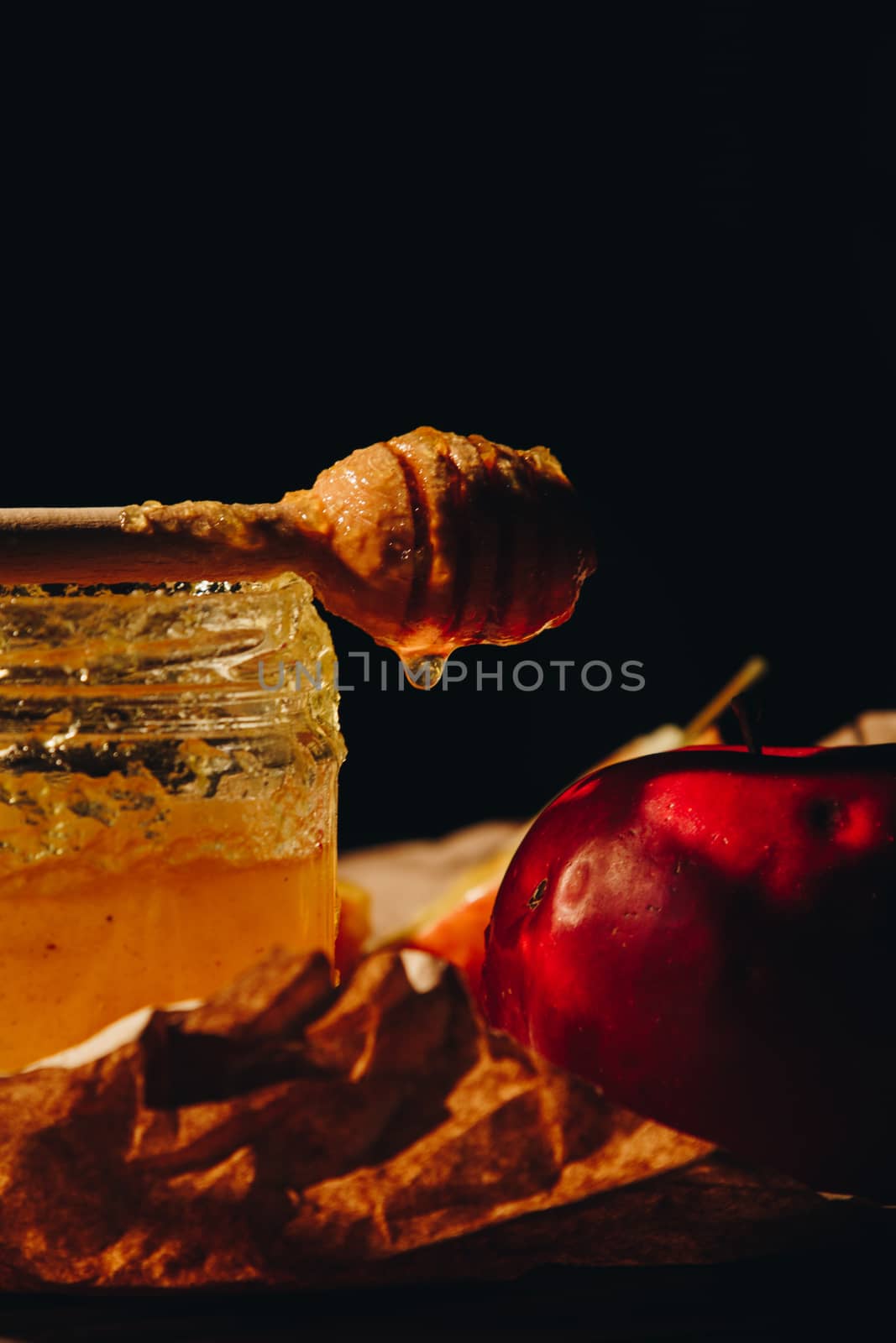 Honey with wooden honey dipper and fruits on wooden table close up