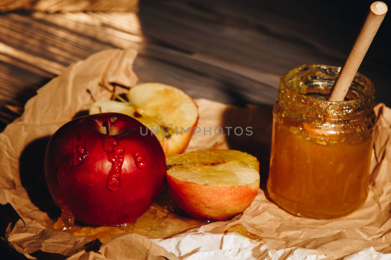 Honey with wooden honey dipper paper napkin and fruits on wooden table close up by yulaphotographer