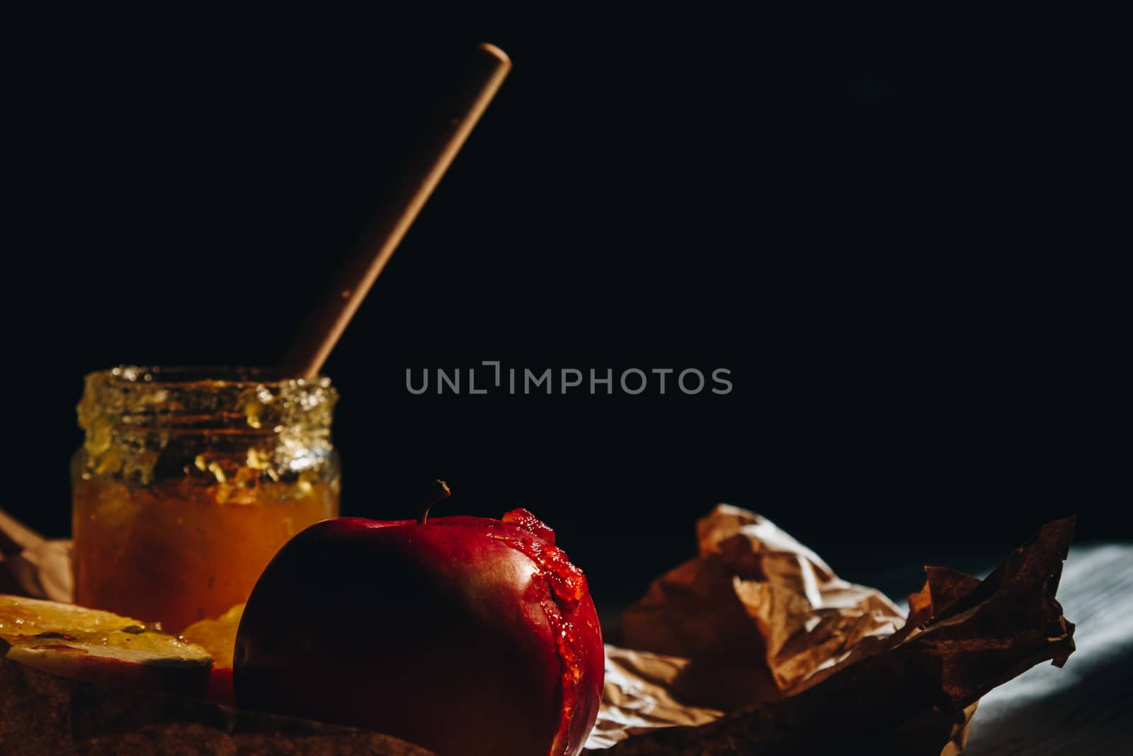 Honey with wooden honey dipper paper napkin and fruits on wooden table close up by yulaphotographer