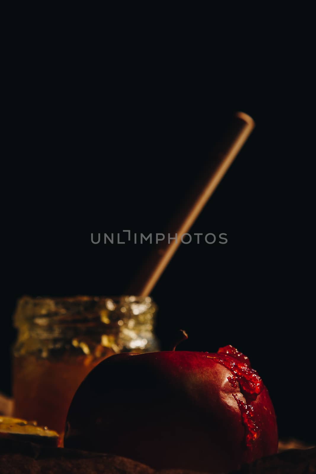 Honey with wooden honey dipper and fruits on wooden table close up