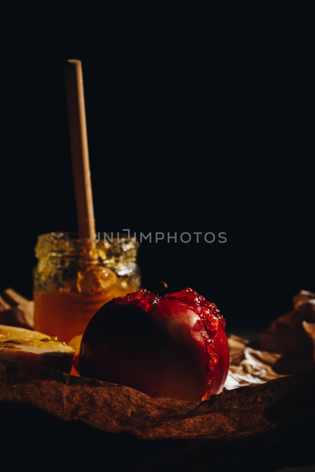 Honey with wooden honey dipper paper napkin and fruits on wooden table close up by yulaphotographer