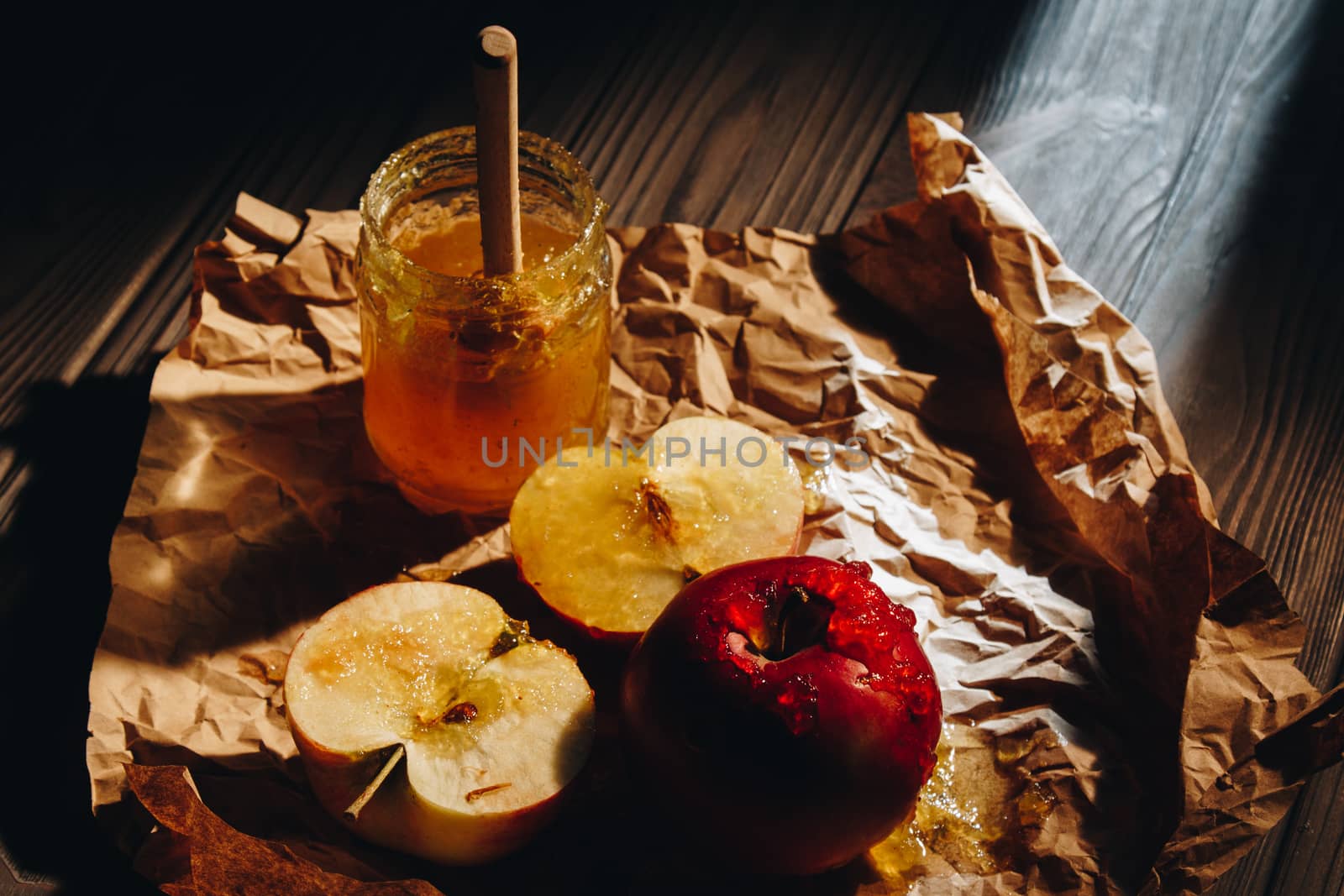 Honey with wooden honey dipper and fruits on wooden table close up