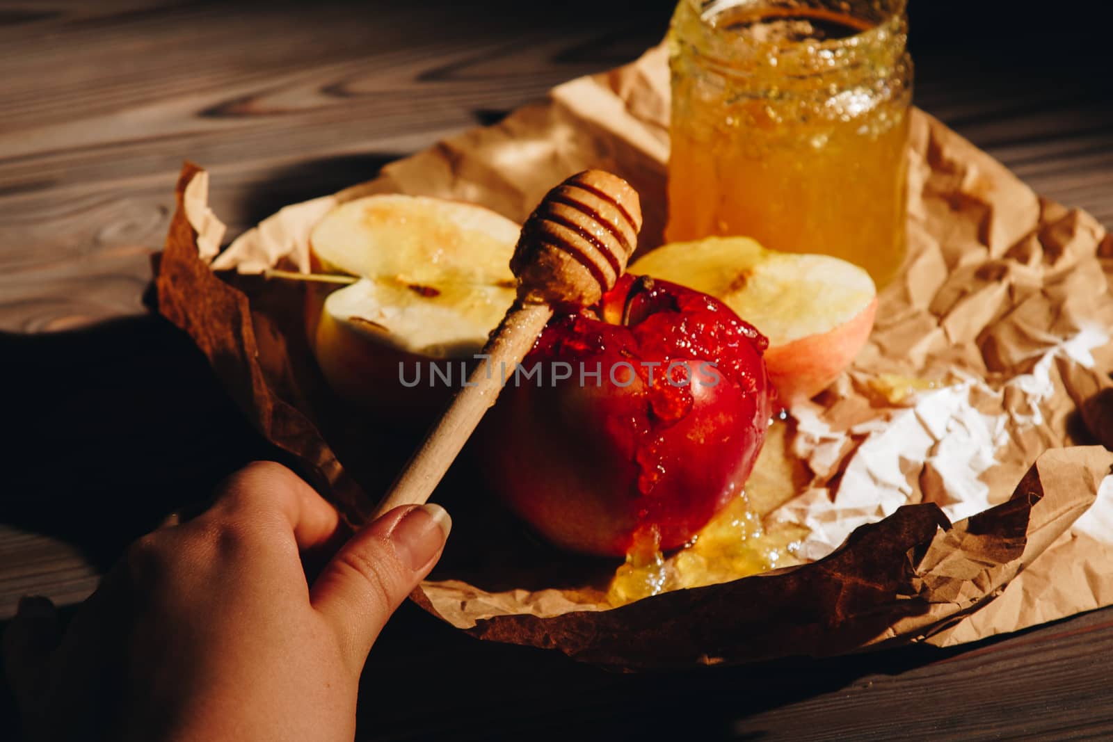 Honey with wooden honey dipper paper napkin and fruits on wooden table close up by yulaphotographer