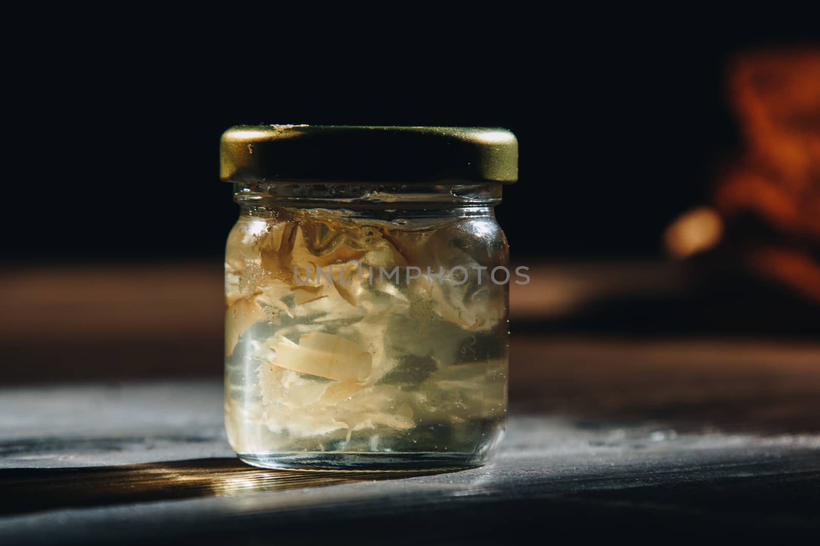 Honey with wooden honey dipper paper napkin and fruits on wooden table close up by yulaphotographer