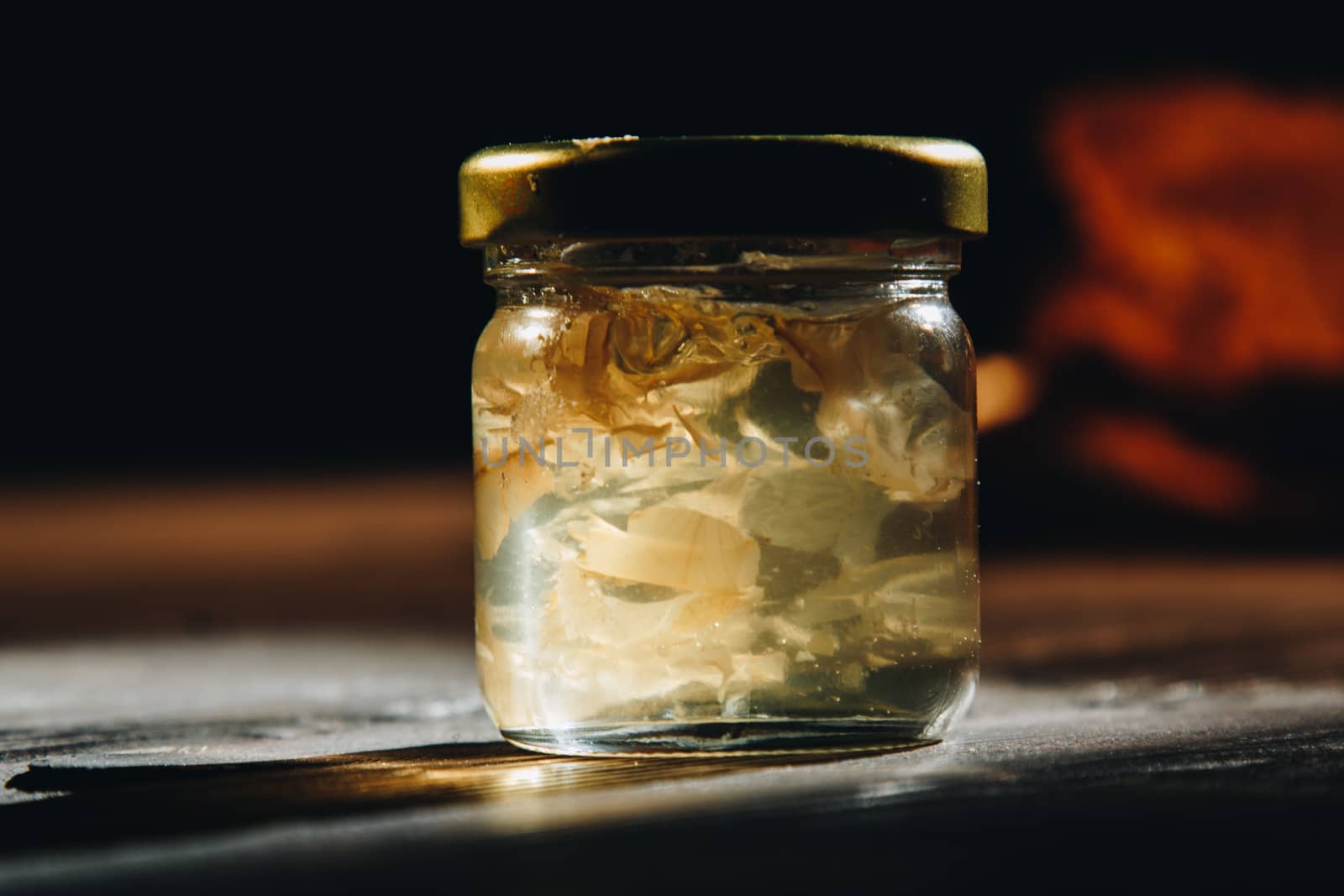 Honey with wooden honey dipper and fruits on wooden table close up