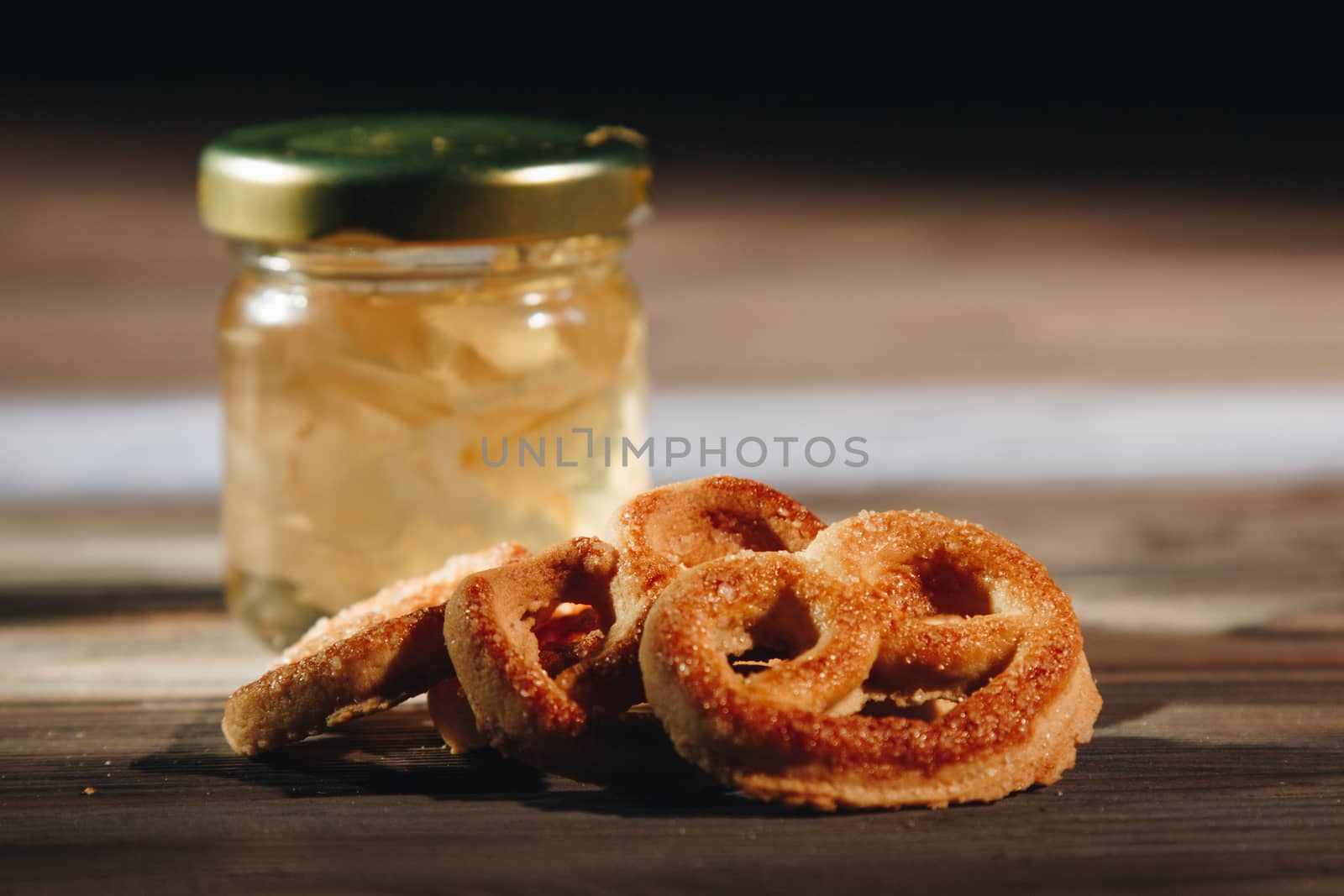 jar of honey with bagels on wooden table close up with honey dipper by yulaphotographer