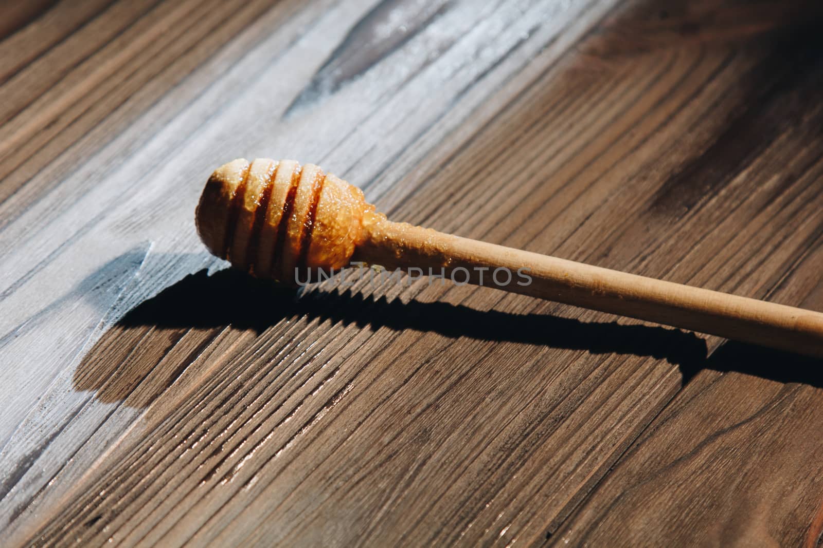 jar of honey with bagels on wooden table close up with honey dipper on black background