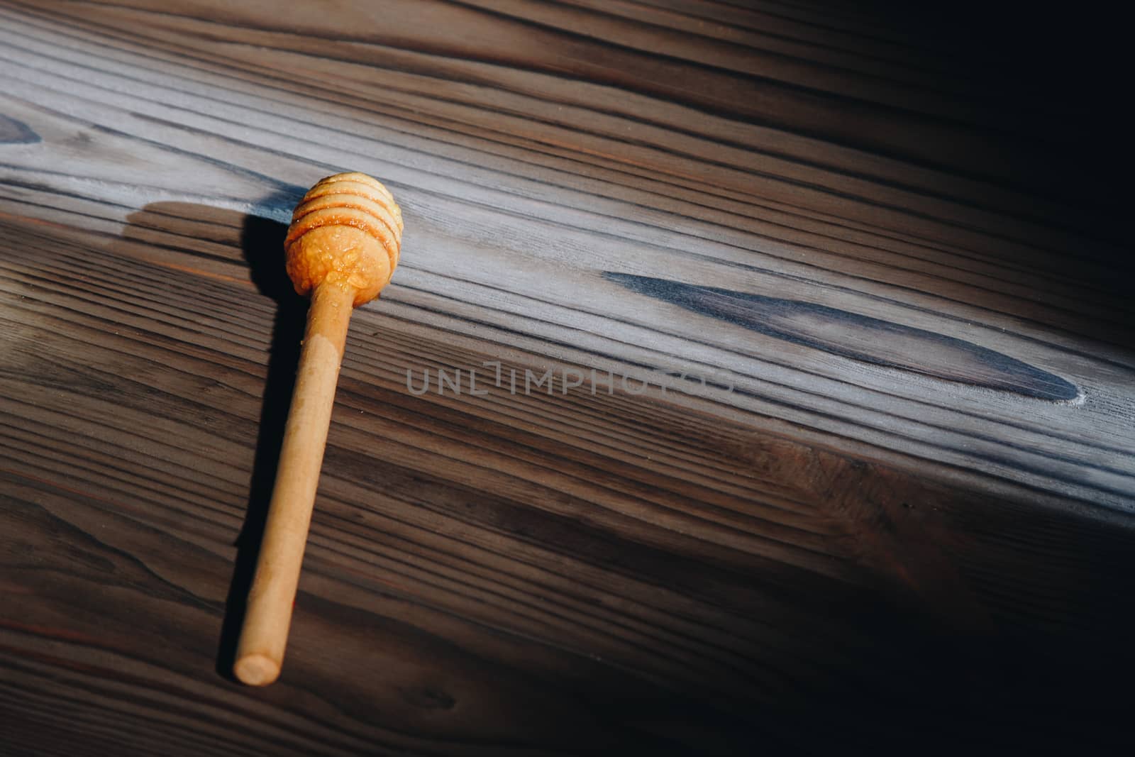 jar of honey with bagels on wooden table close up with honey dipper by yulaphotographer