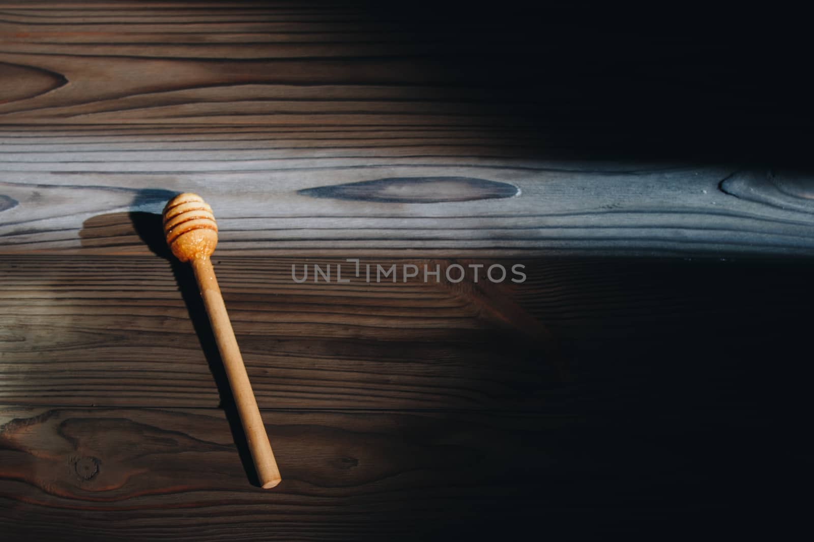 jar of honey with bagels on wooden table close up with honey dipper on black background