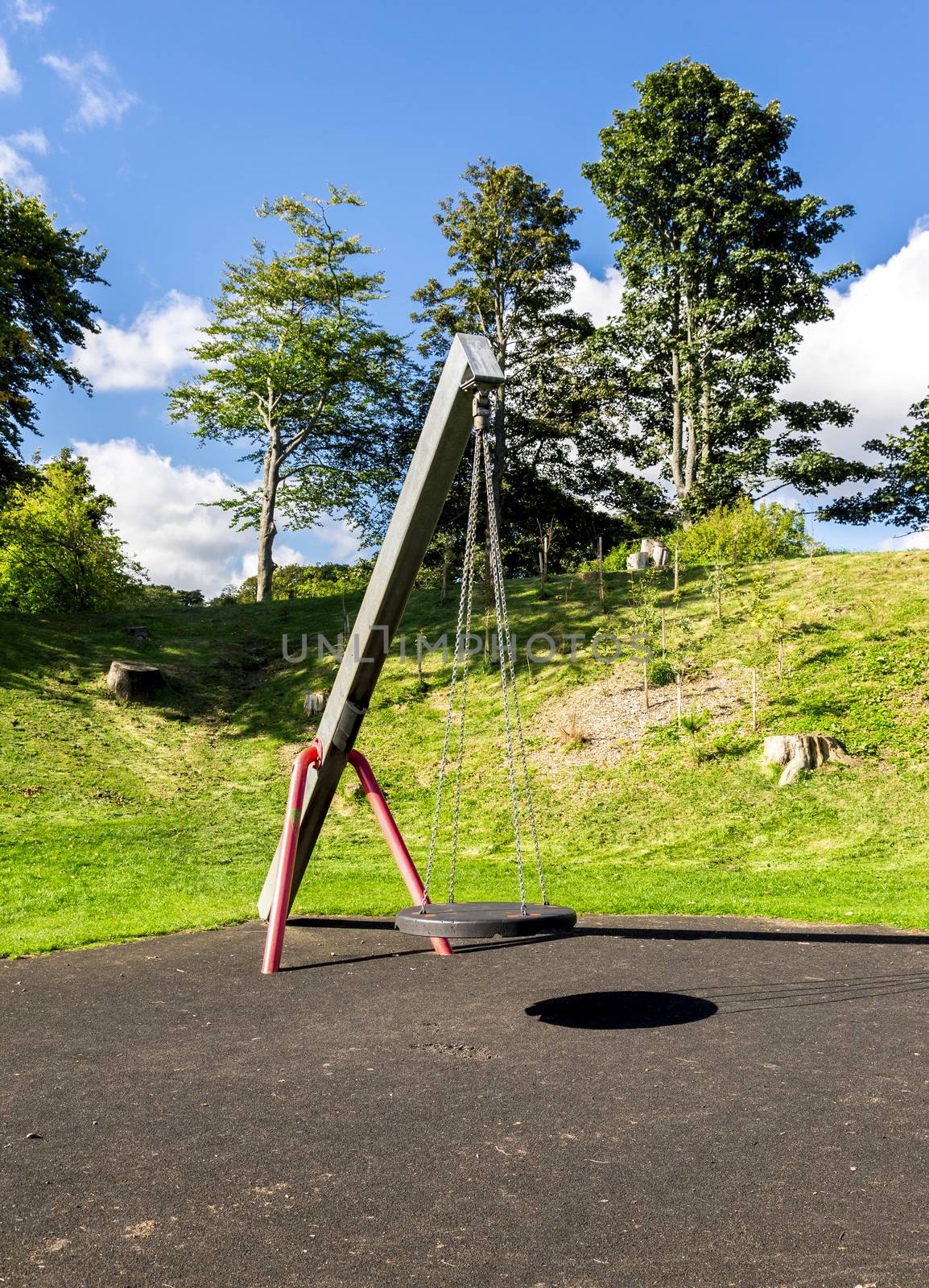 A swing with a rubber round seat hanging on four chains in Duthie park playground, Aberdeen, Scotland