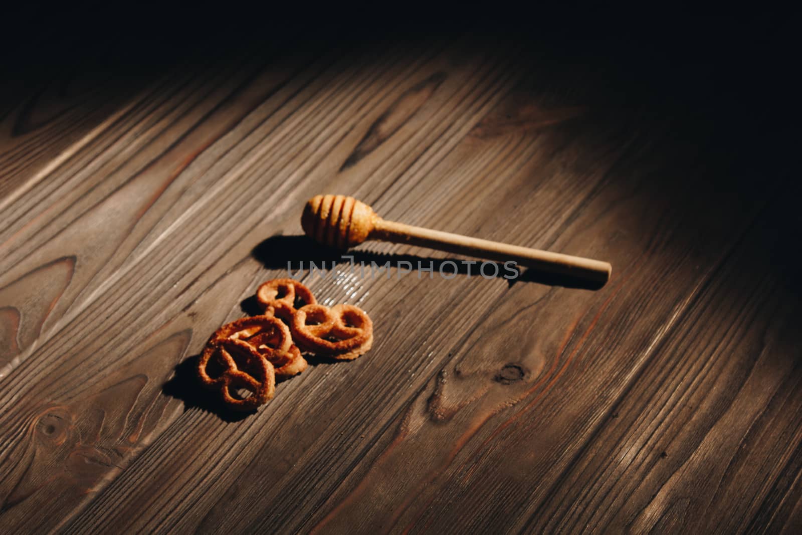 jar of honey with bagels on wooden table close up with honey dipper by yulaphotographer