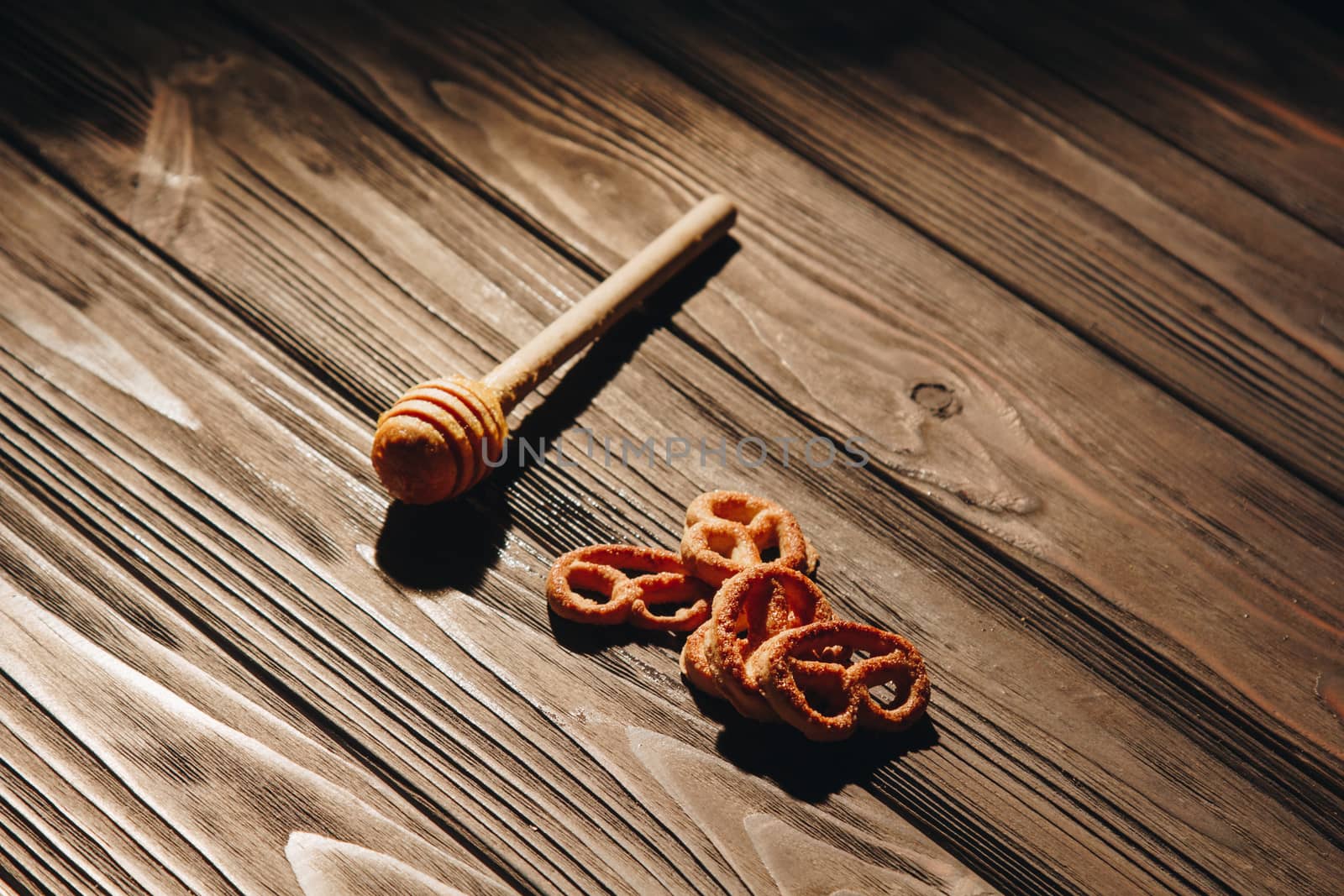 jar of honey with bagels on wooden table close up with honey dipper on black background