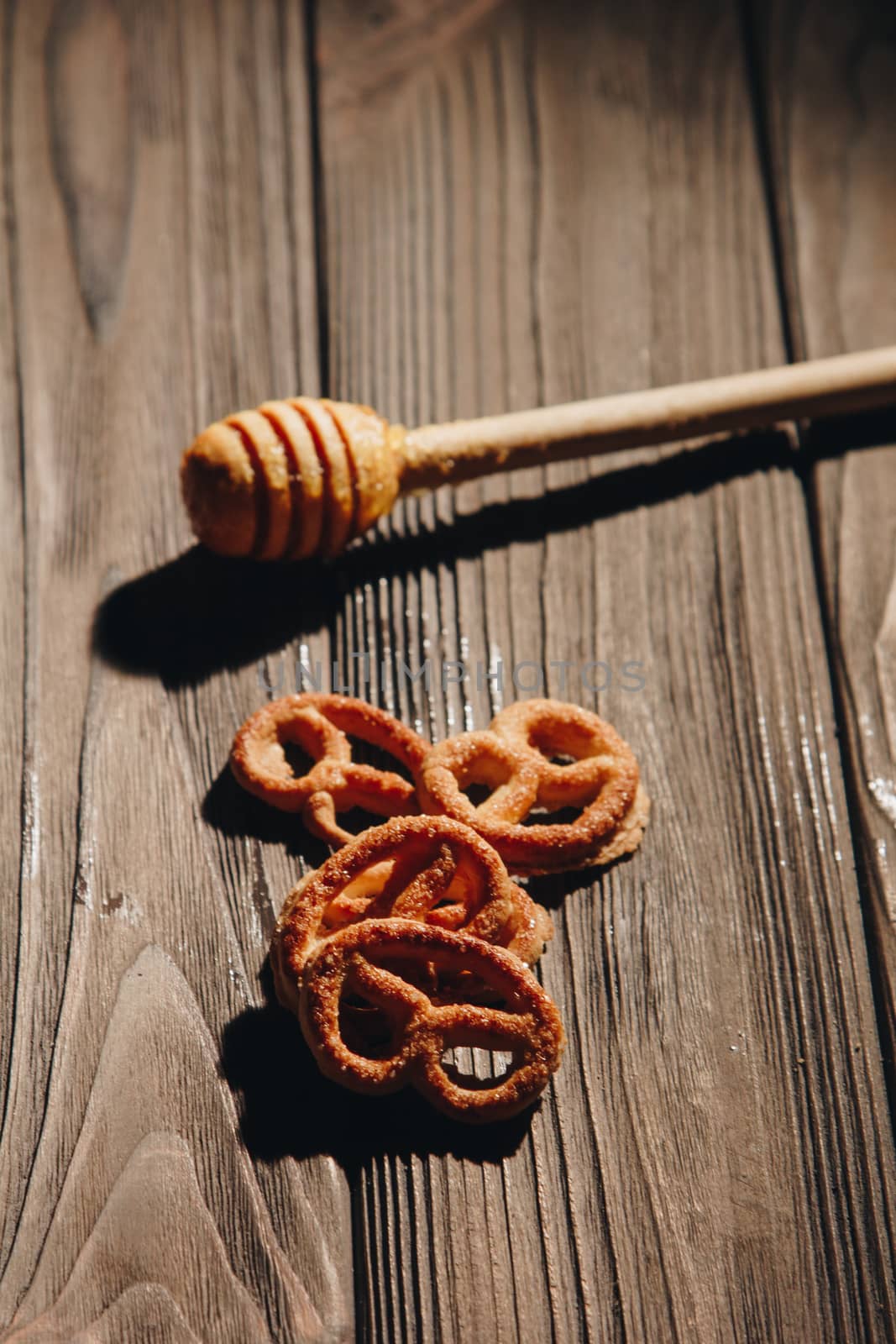 jar of honey with bagels on wooden table close up with honey dipper on black background