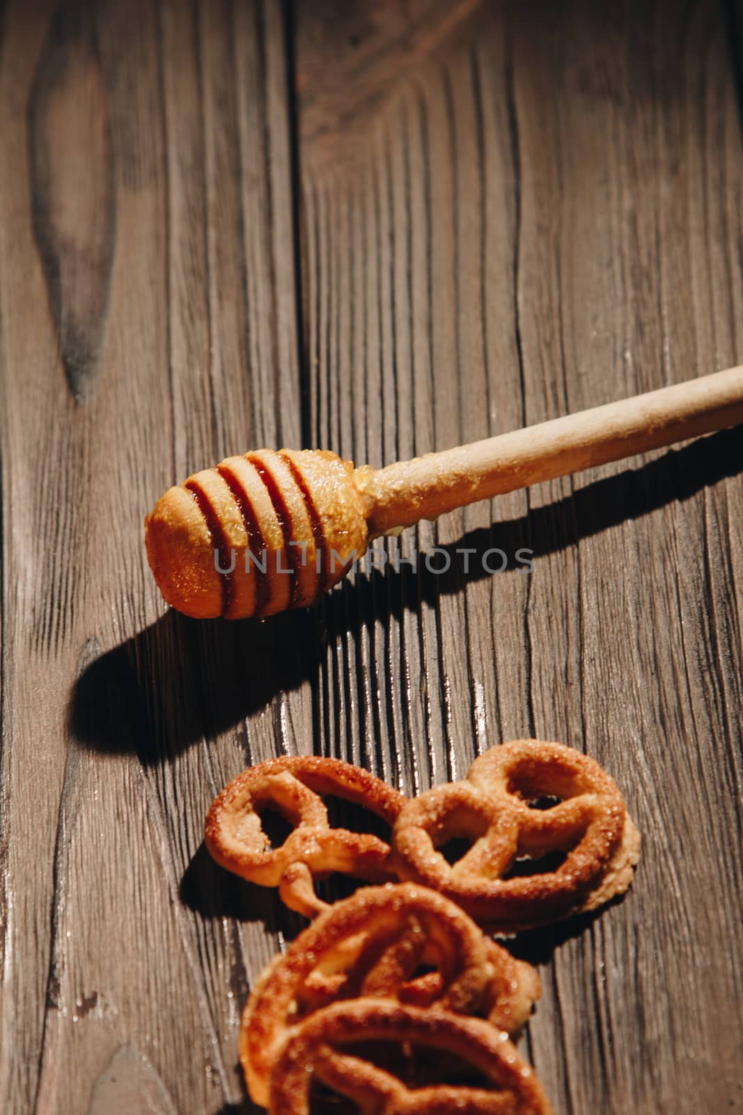 jar of honey with bagels on wooden table close up with honey dipper by yulaphotographer