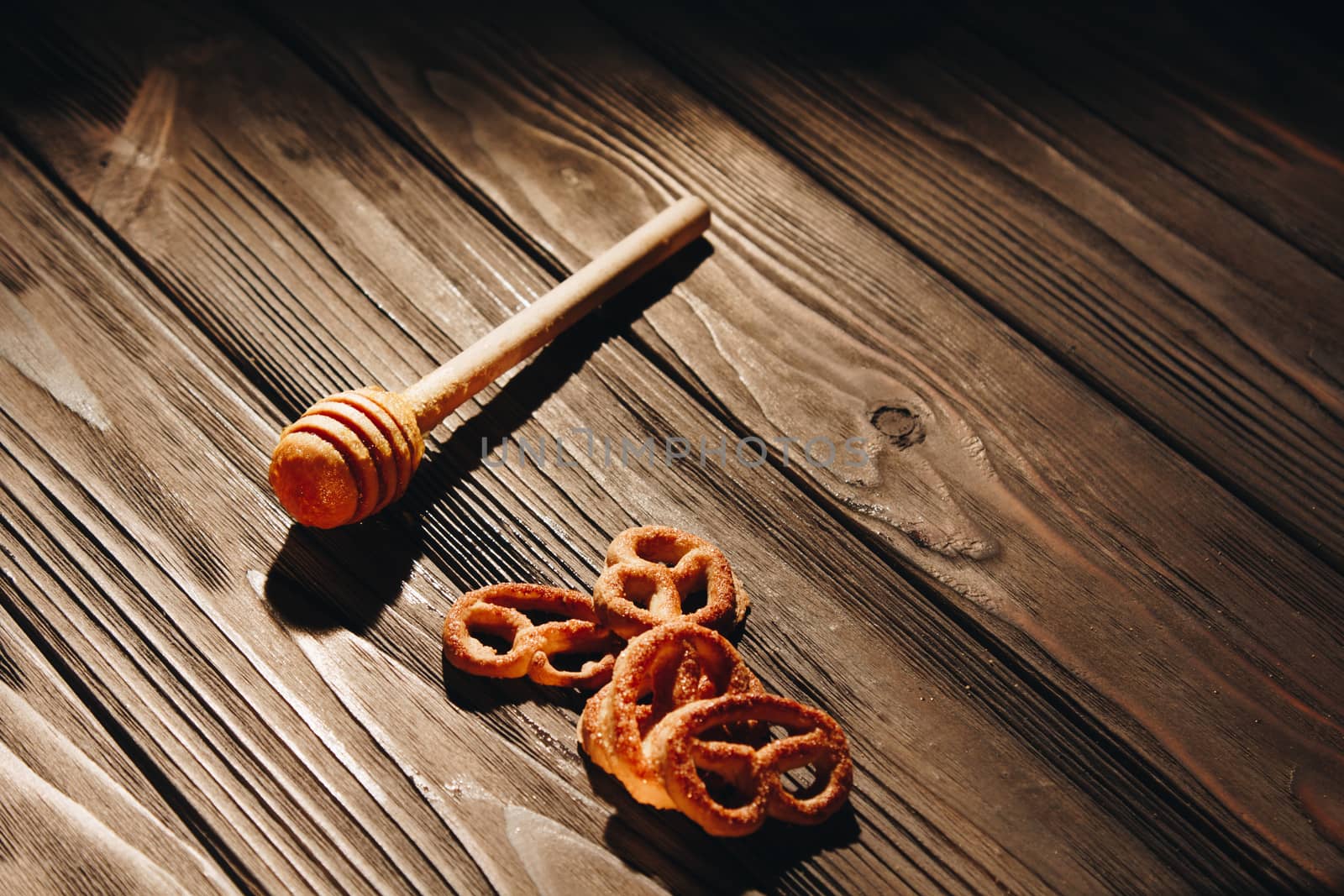 jar of honey with bagels on wooden table close up with honey dipper on black background