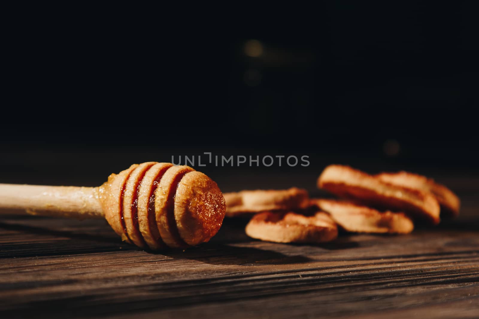 jar of honey with bagels on wooden table close up with honey dipper by yulaphotographer