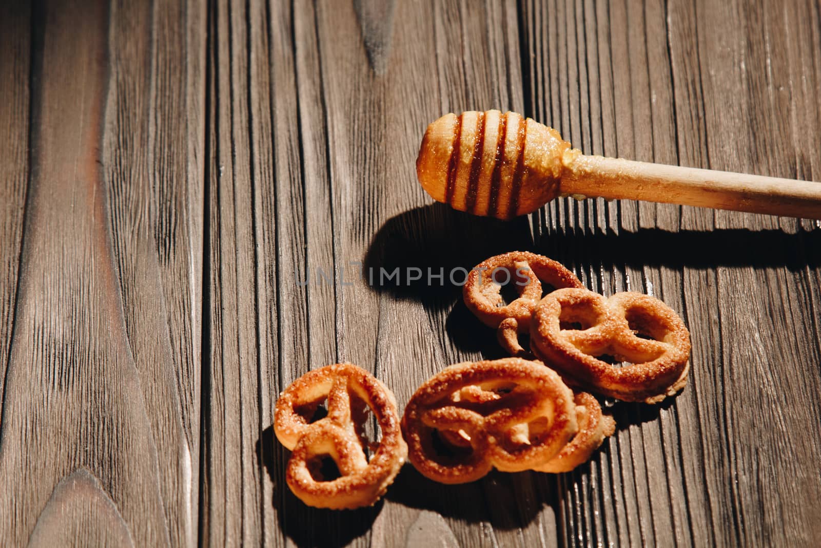 jar of honey with bagels on wooden table close up with honey dipper on black background