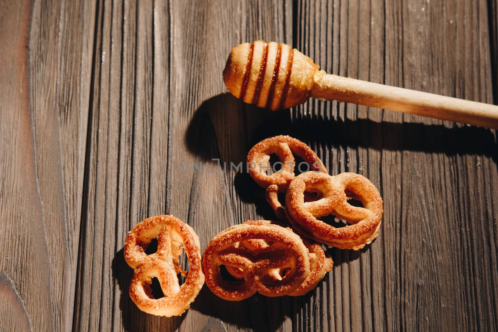 jar of honey with bagels on wooden table close up with honey dipper on black background