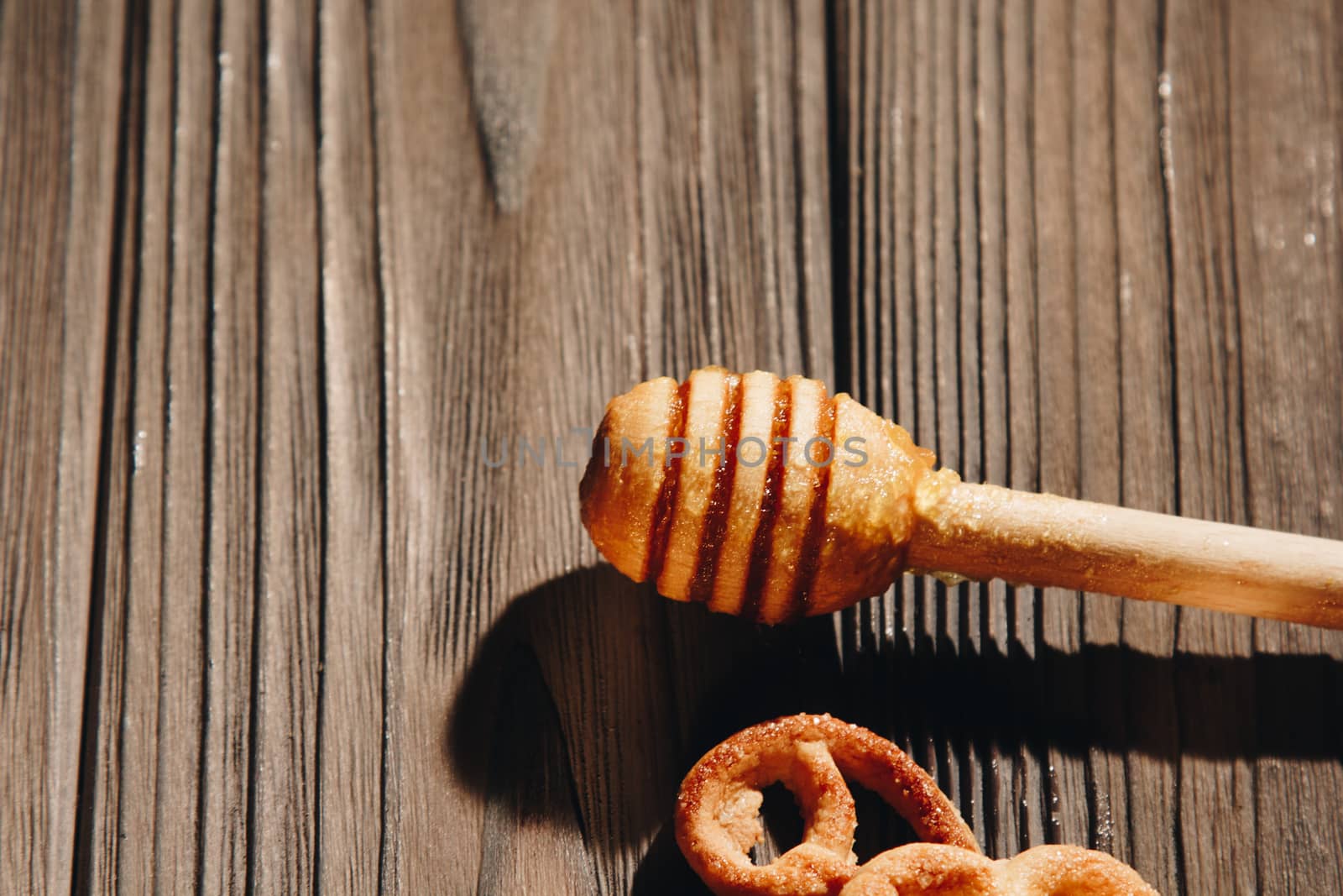 jar of honey with bagels on wooden table close up with honey dipper by yulaphotographer