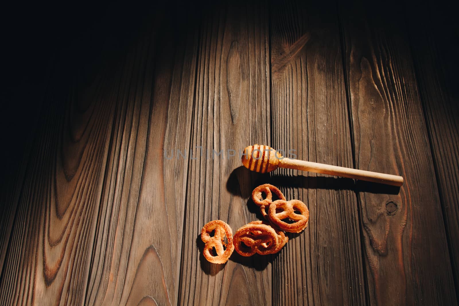 jar of honey with bagels on wooden table close up with honey dipper on black background