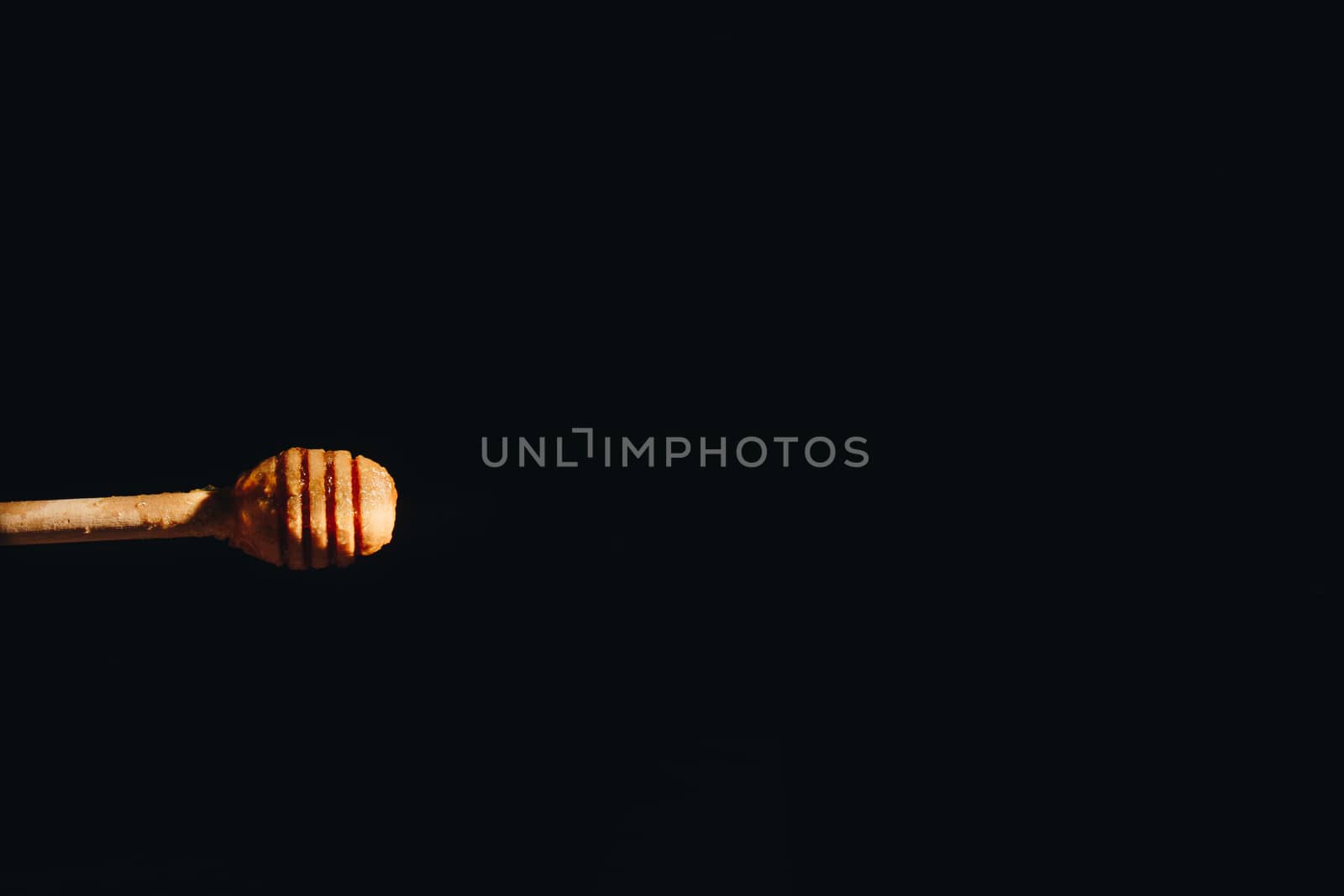 jar of honey with bagels on wooden table close up with honey dipper by yulaphotographer