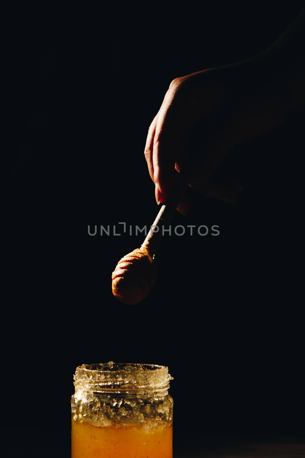 jar of honey with bagels on wooden table close up with honey dipper on black background