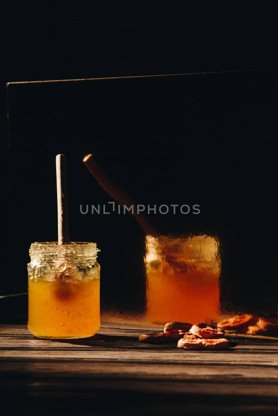 jar of honey with bagels on wooden table close up with honey dipper by yulaphotographer