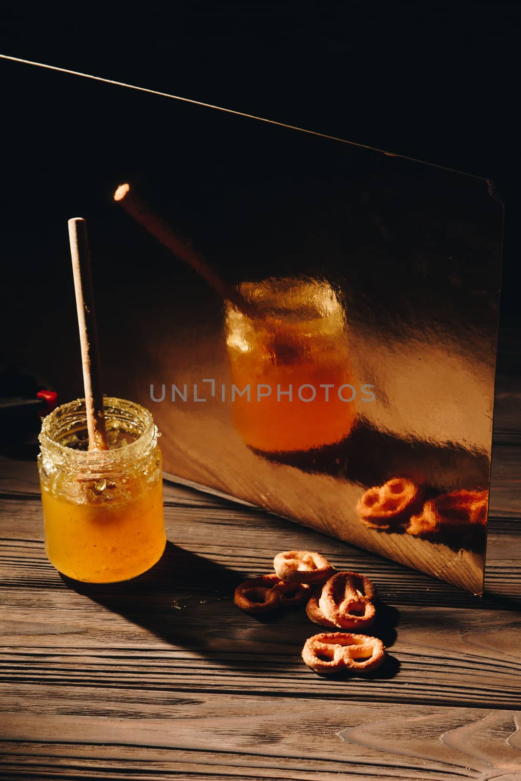 jar of honey with bagels on wooden table close up with honey dipper on black background