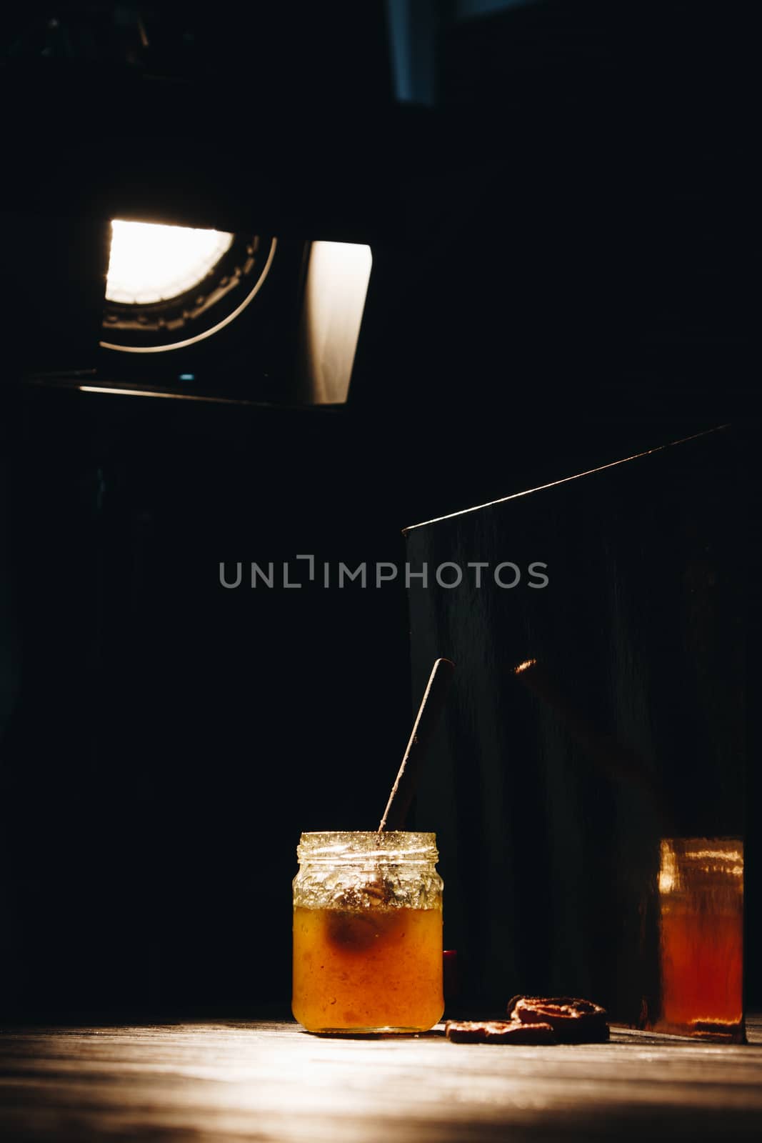 jar of honey with bagels on wooden table close up with honey dipper by yulaphotographer