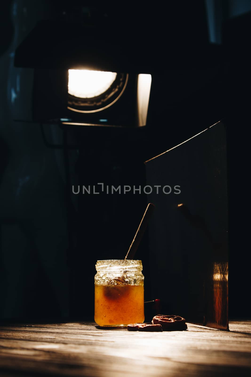 jar of honey with bagels on wooden table close up with honey dipper by yulaphotographer