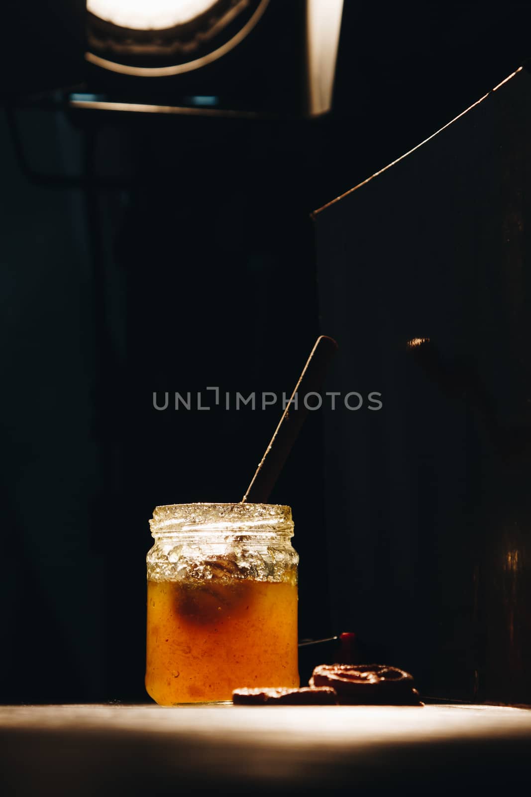 jar of honey with bagels on wooden table close up with honey dipper on black background