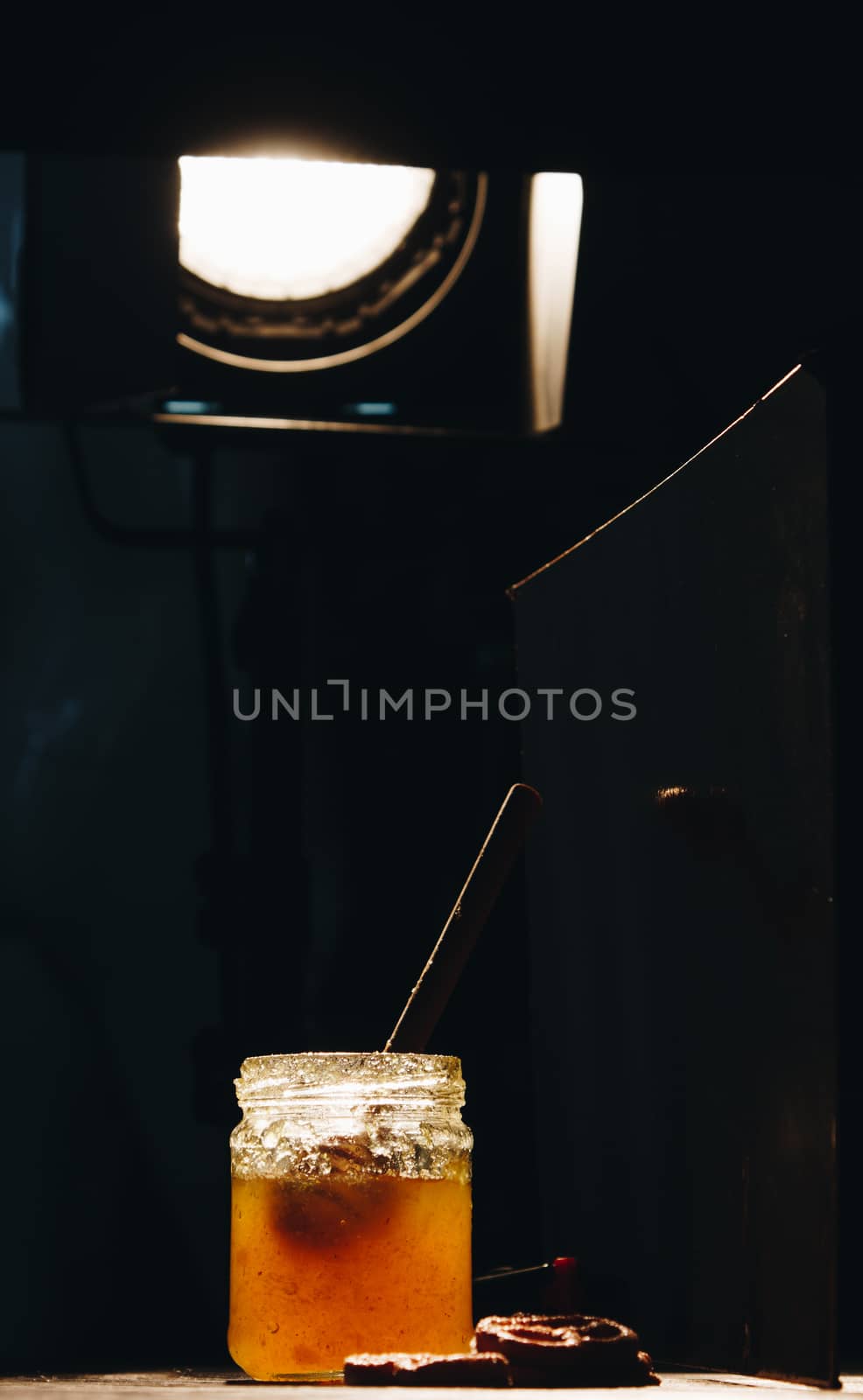 jar of honey with bagels on wooden table close up with honey dipper on black background