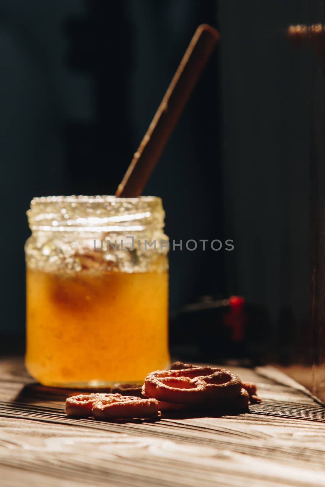 jar of honey with bagels on wooden table close up with honey dipper on black background