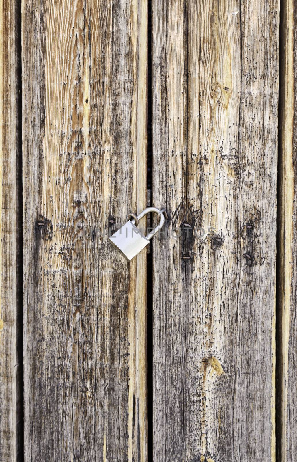 Wooden door locked with a padlock, detail of a textured, protection