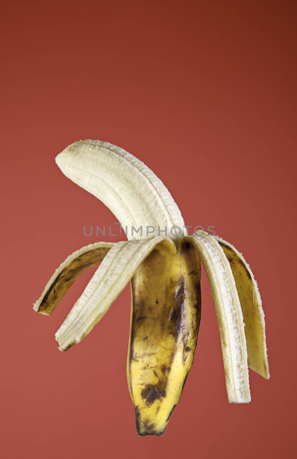 Banana peel, peeled tropical fruit detail on red background
