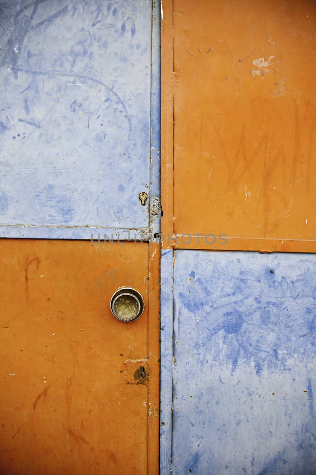 Orange and blue closed door, detail of a decorated door in the city, loneliness and abandonment
