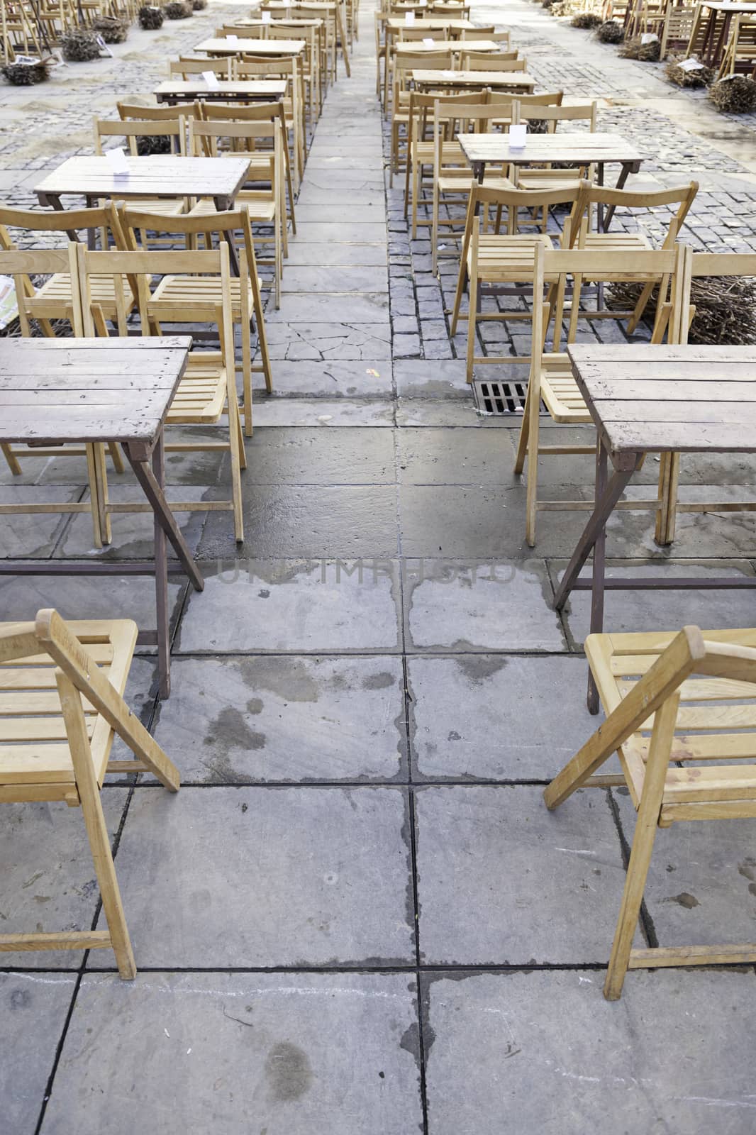 Wooden tables and chairs in the street by esebene