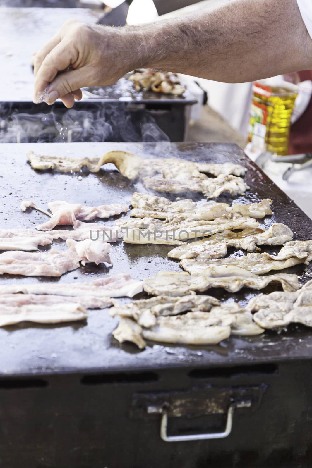 Frying bacon, pork detail a sarte frying, cooking in the street, holding
