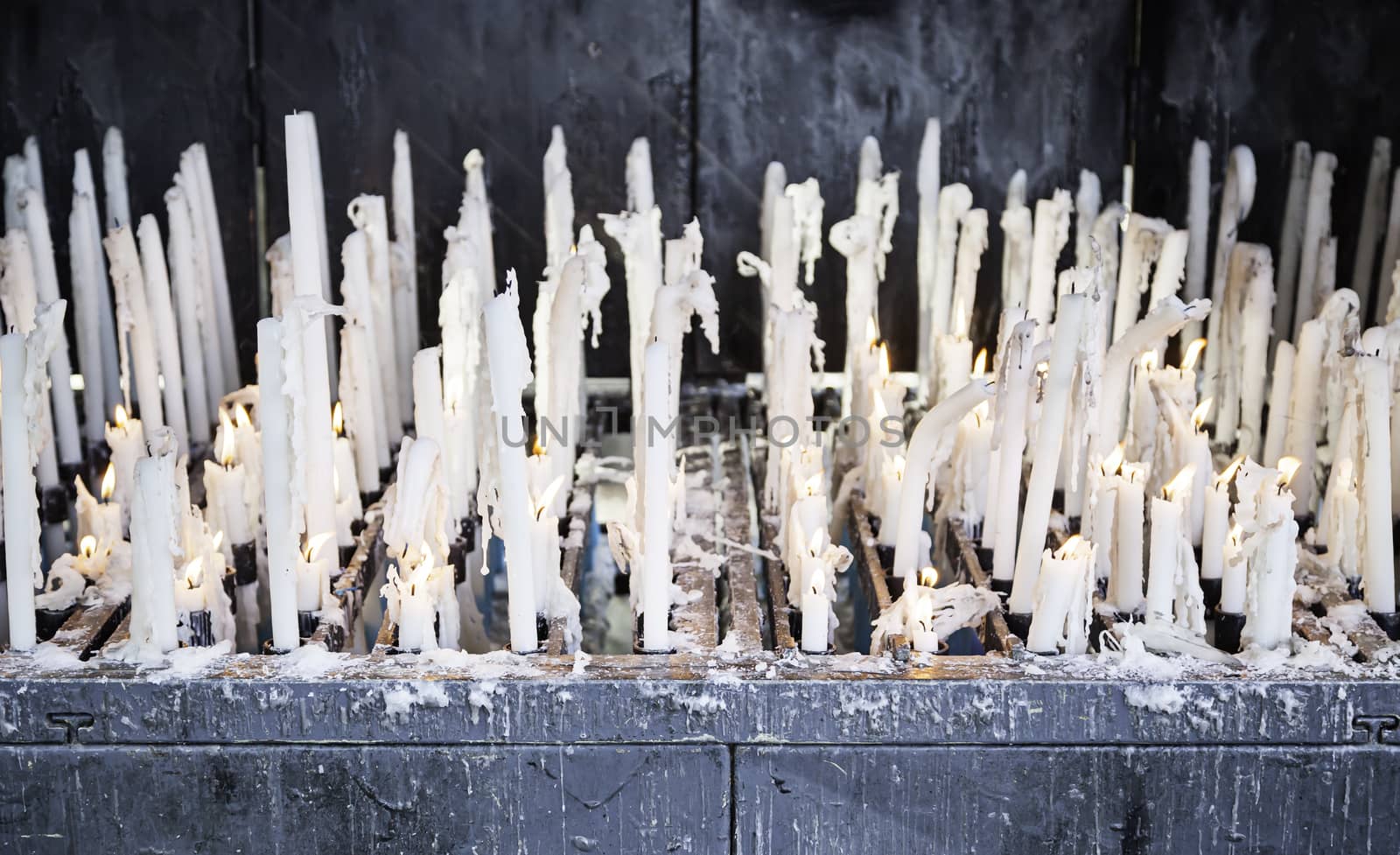 Burning candles in a church, detail of lighted wax candles to pray Christian tradition, faith