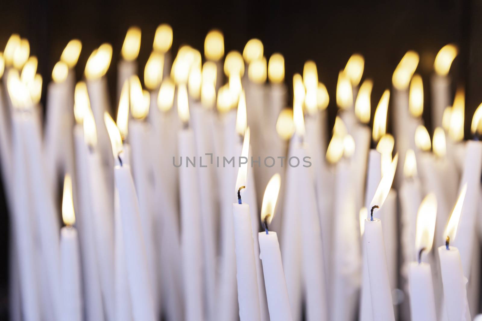 Burning candles in a church, detail of lighted wax candles to pray Christian tradition, faith