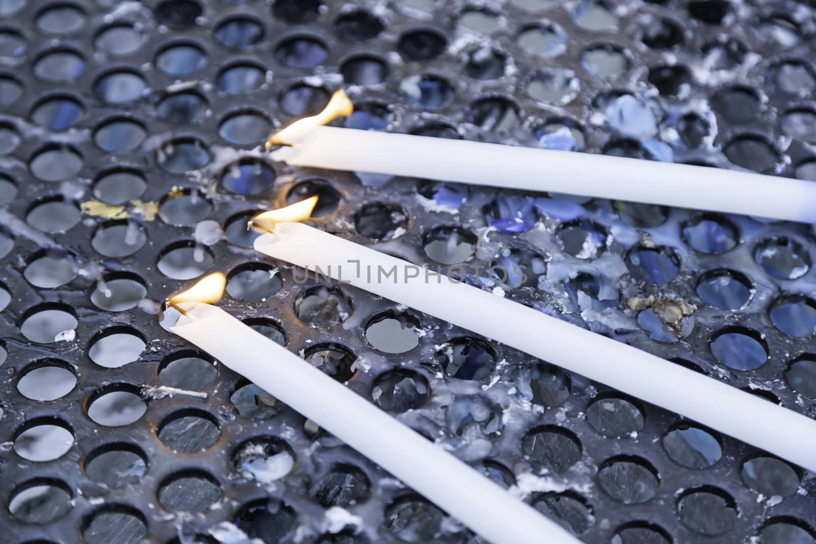 Wax candles elongated, detail of blue candles lit, belief and religion