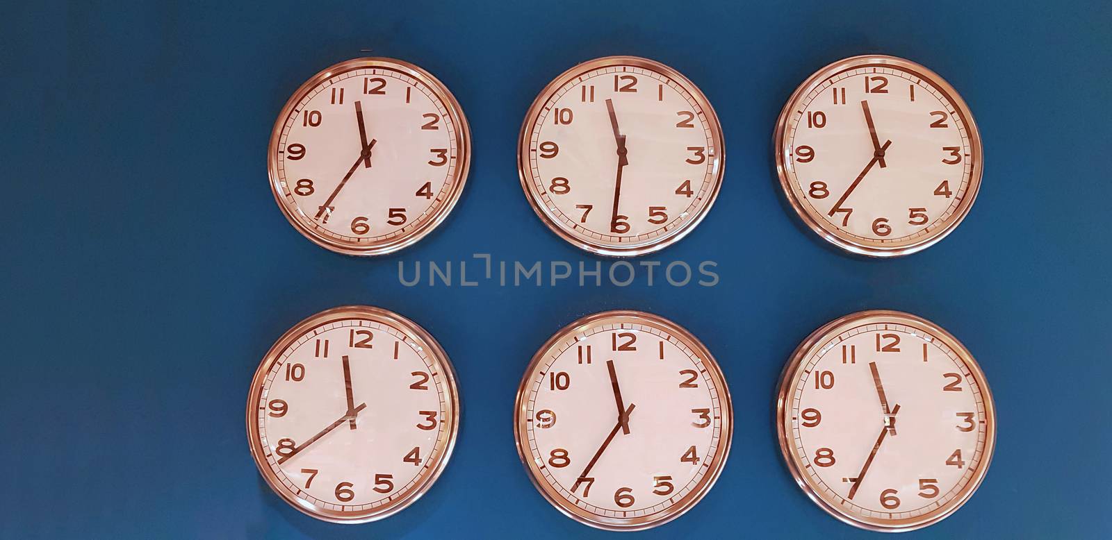 Six wall clocks with twelve hour clock face on blue background