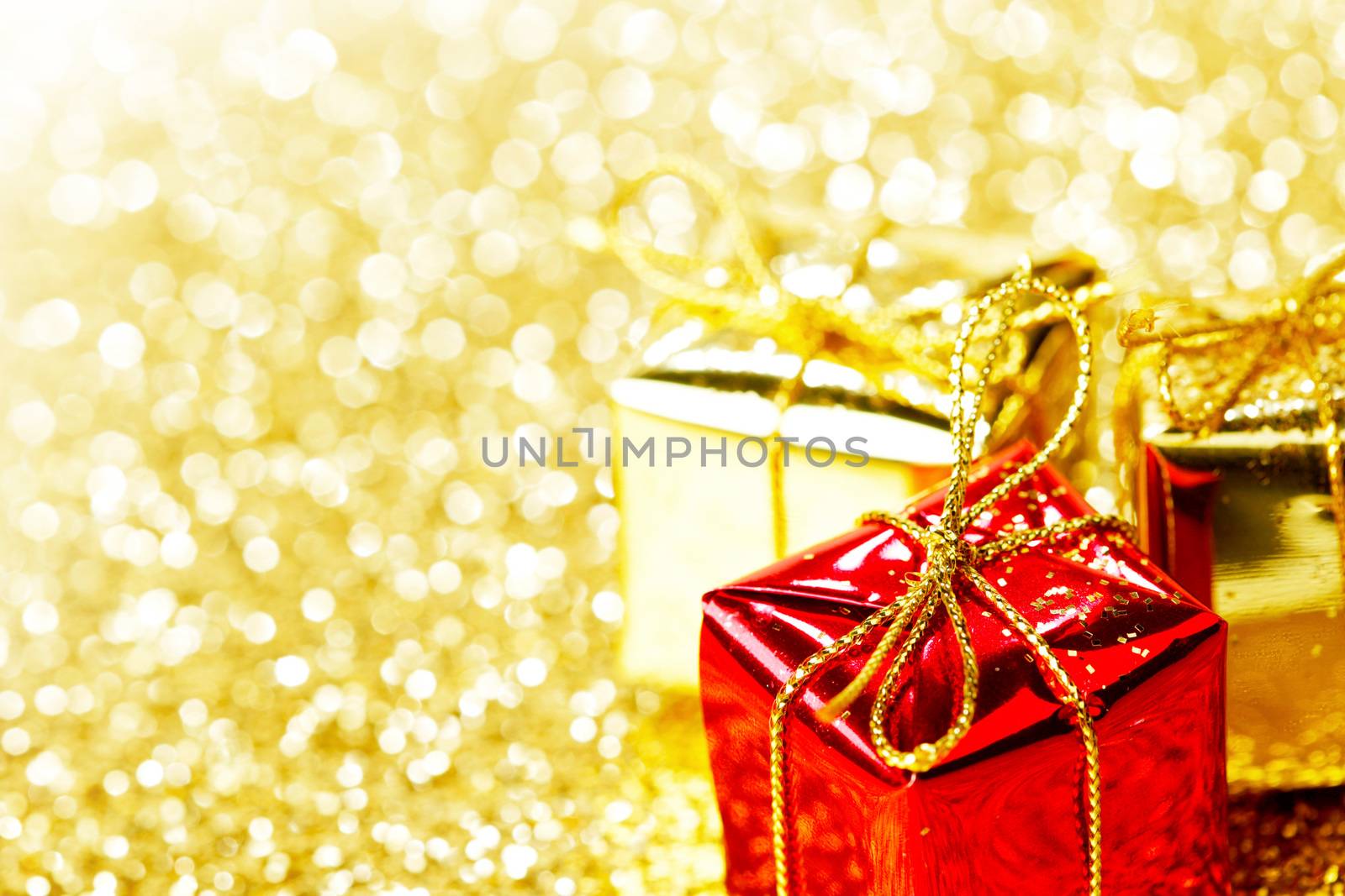 Decorative red and gold boxes with holiday gifts on shiny glitter background