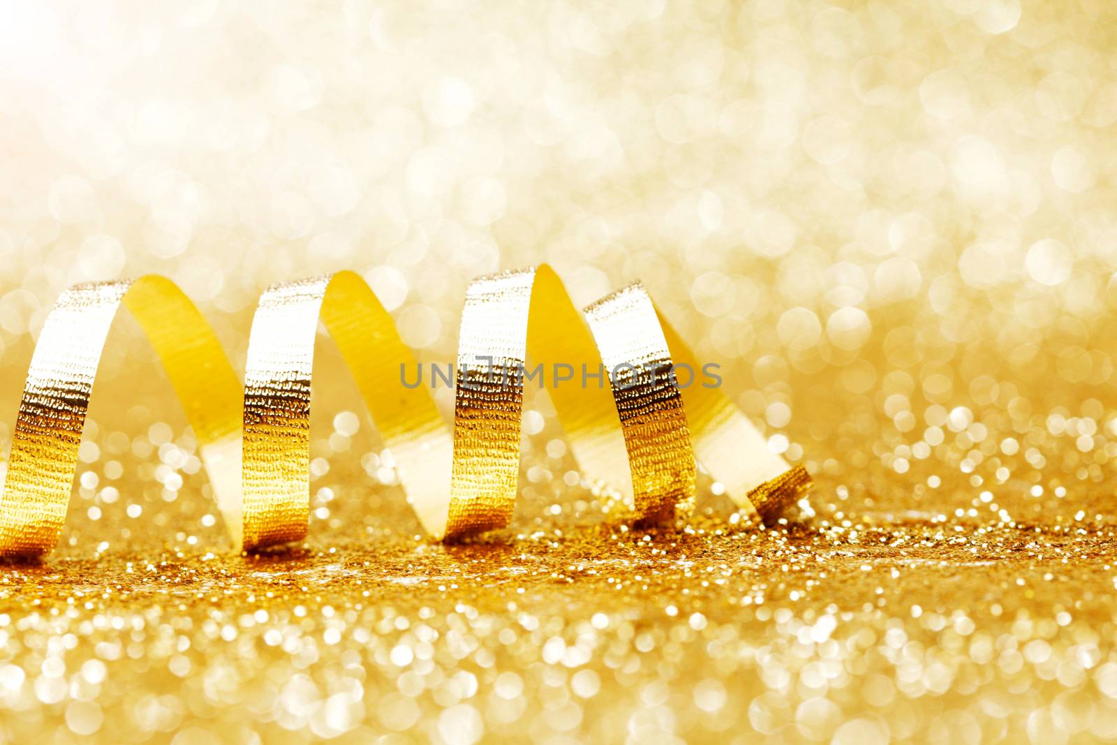 Golden curly ribbon decoration on glitter background close-up