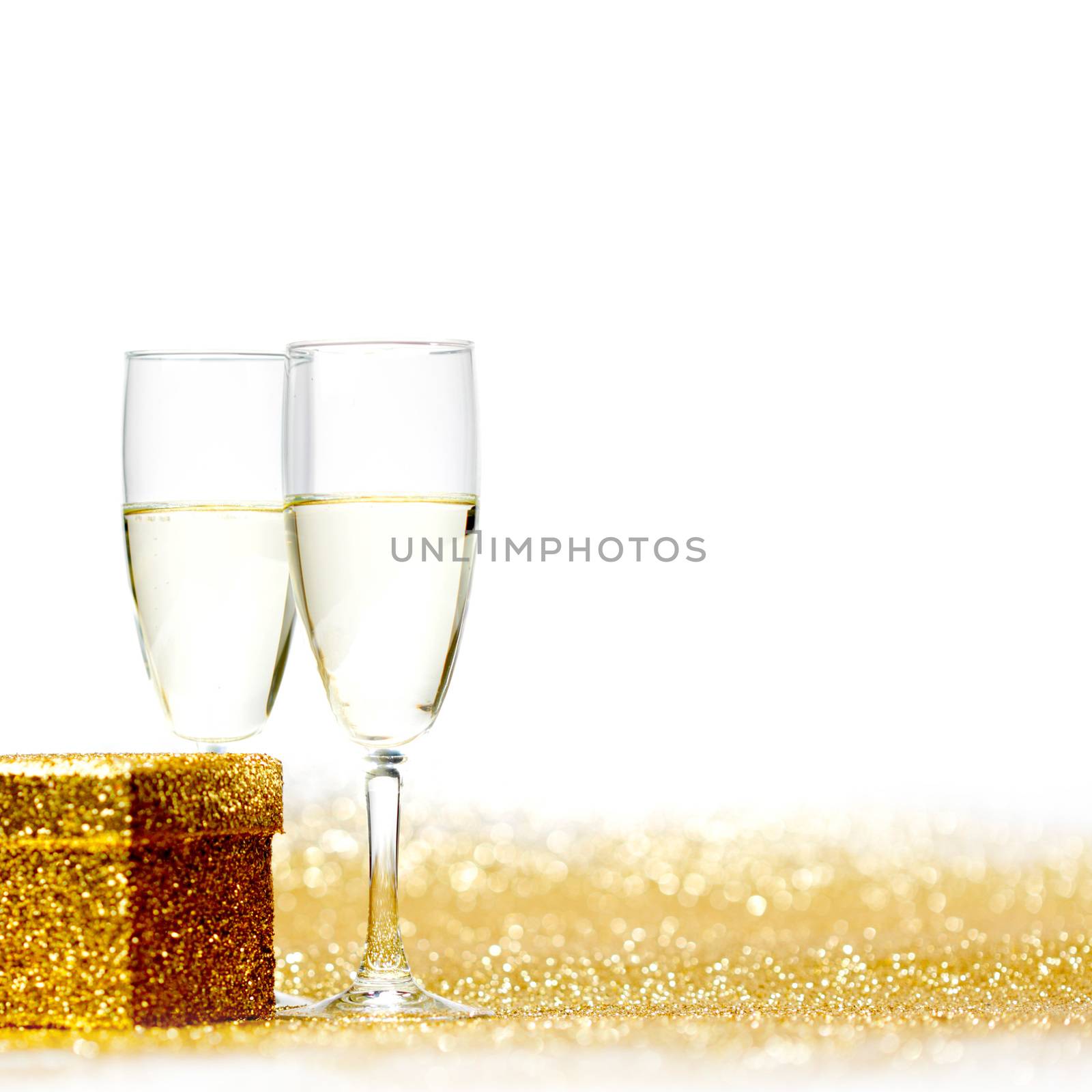 Glasses of champagne and gift on glitters isolated on white