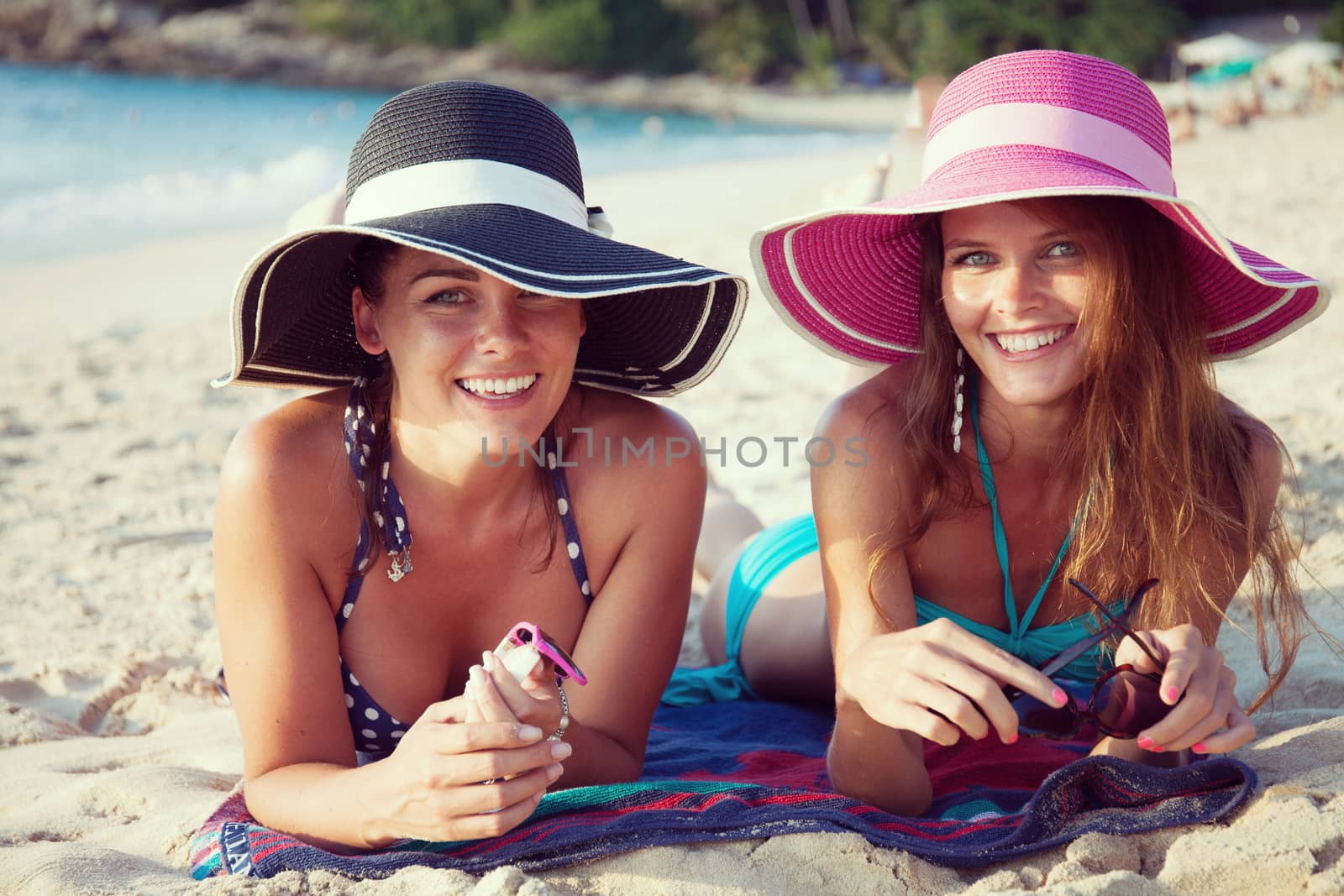 Beautiful young women in sunhats laying on beach