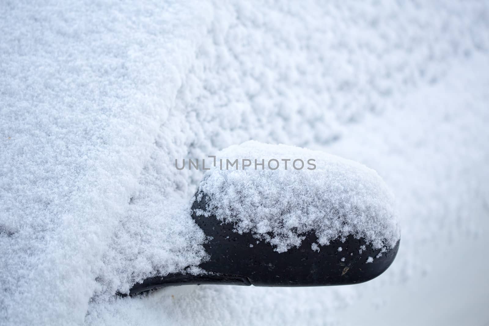 Snow overnight blanketed the landscape, including the roads and cars. A close up of a front car and side mirror