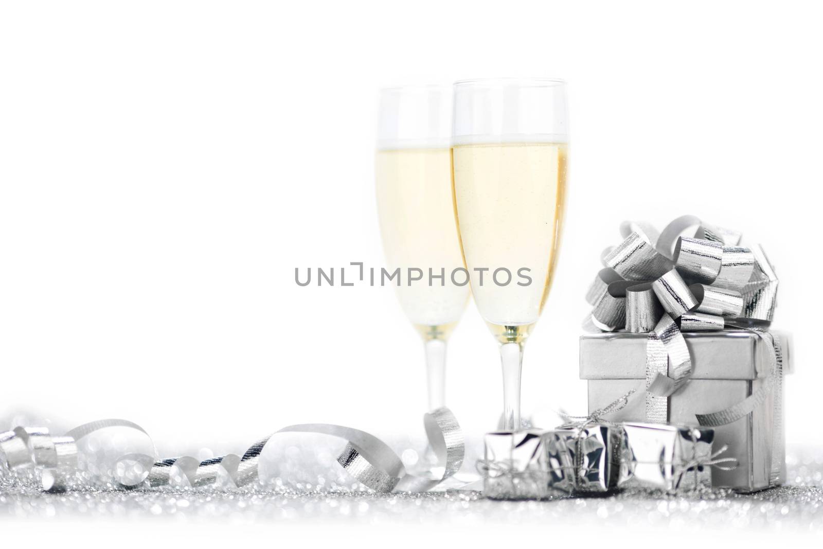 Two elegant flutes of sparkling champagne with decorative silver gifts